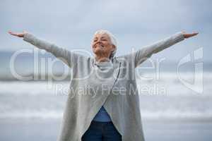 Senior woman with arms outstretched standing on the beach