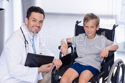 Portrait of smiling doctor and disable boy in corridor