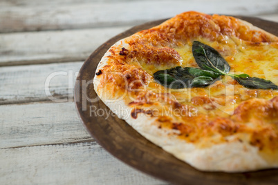 Italian pizza in a chopping board on a wooden plank