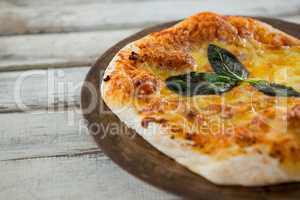 Italian pizza in a chopping board on a wooden plank