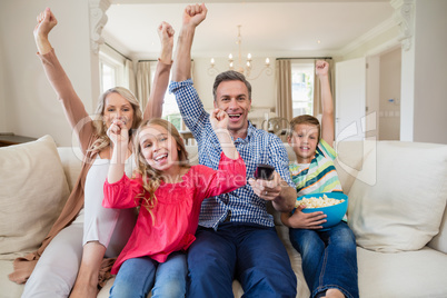 Family watching soccer match on television in living room