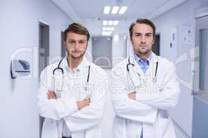 Portrait of doctors standing with arms crossed in corridor