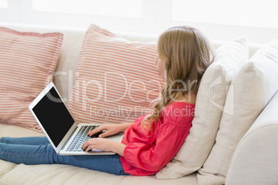 Girl using laptop on sofa in living room