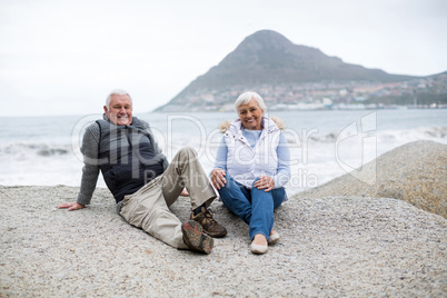 Portrait of senior couple sitting on rock at beach