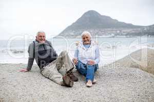 Portrait of senior couple sitting on rock at beach