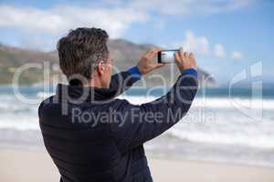 Mature man photographing scenery using cell phone