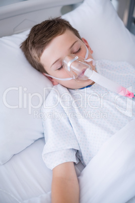 Boy patient wearing oxygen mask lying on hospital bed