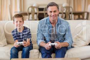 Father and son playing video game in living room