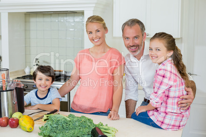 Portrait of parents and their two kids standing in kitchen