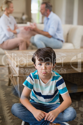 Sad boy listening to his parents arguing