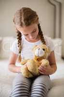 Girl holding a teddy bear on bed in bedroom