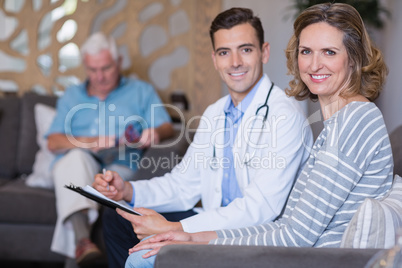 Portrait of doctor and woman sitting on sofa with medical report