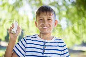 Boy showing his asthma inhaler in park
