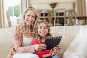Mother and daughter using digital tablet at home