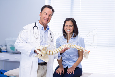 Portrait of physiotherapist and patient holding spine model