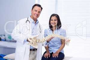 Portrait of physiotherapist and patient holding spine model