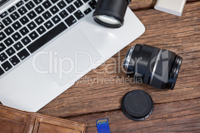 Close-up of digital camera, lens, memory card, laptop on table