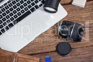 Close-up of digital camera, lens, memory card, laptop on table