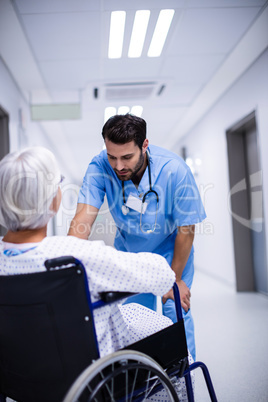 Male doctor interacting with senior patient on wheelchair