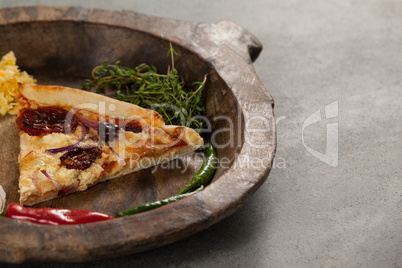 Spices and slice of italian pizza in wooden bowl