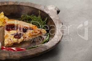 Spices and slice of italian pizza in wooden bowl