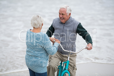 Senior couple standing with bicycles on the beach