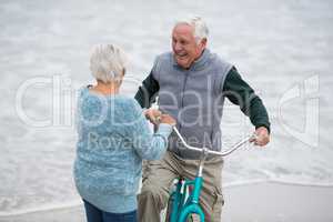 Senior couple standing with bicycles on the beach