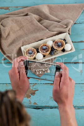 Photographer clicking a picture of dessert using smartphone