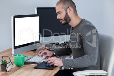 Male photographer using graphic tablet at desk