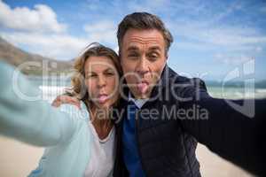 Mature couple sticking out tongue while taking selfie