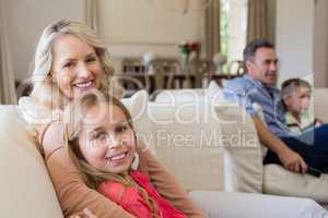 Smiling mother and daughter sitting together in living room