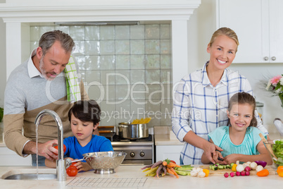 Parents assisting a kids to chop and clean the vegetables in kitchen