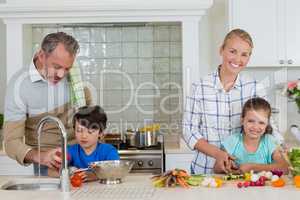 Parents assisting a kids to chop and clean the vegetables in kitchen