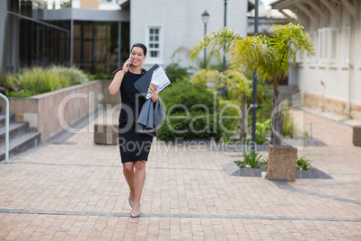 Businesswoman holding clipboard and talking on mobile phone