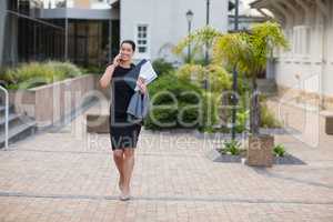 Businesswoman holding clipboard and talking on mobile phone