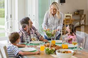 Mother serving food to family on dinning table