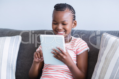 Girl sitting on sofa using digital tablet