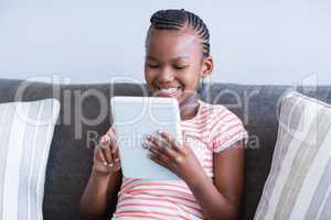 Girl sitting on sofa using digital tablet