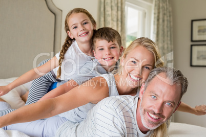 Happy family stacking on top of each other on the bed