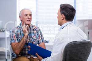 Senior man showing neck pain to doctor