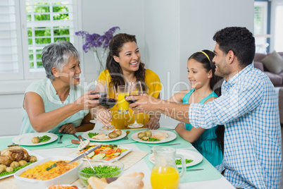 Happy mutigeneration family toasting a glasses of red wine while having meal