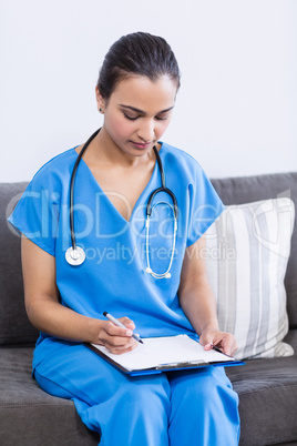 Female doctor writing on clipboard