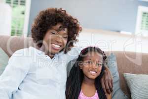 Portrait of mother and daughter sitting on sofa in living room