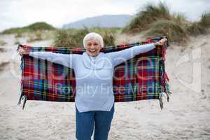 Senior woman with arms outstretched standing on the beach