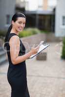 Happy businesswoman holding mobile phone and clipboard