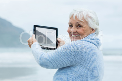 Senior woman photographing scenery using digital tablet