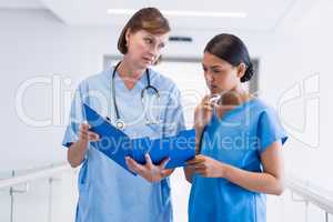 Nurse and doctor discussing over clipboard