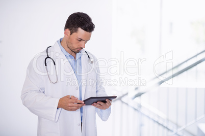 Doctor using digital tablet in corridor