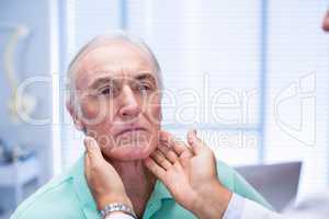 Doctor examining senior patients neck