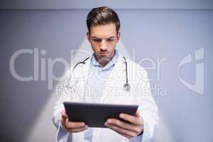 Doctor using digital tablet in corridor